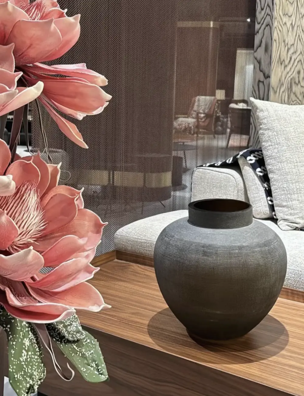 Inside the Emerald Casa showroom: a textured vessel on walnut beside a woven sofa